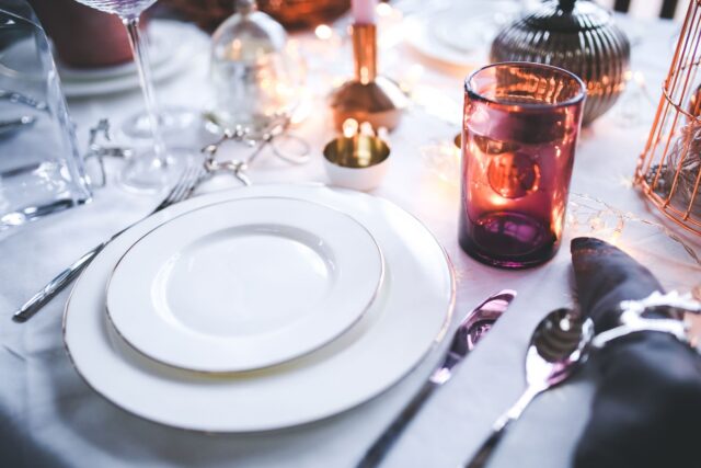 Masă pregătită pentru două persoane, cu o lumânare aprinsă și fără telefoane pe masă
