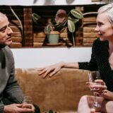 Un cuplu la masa din bucătărie, cu un caiet și o cafea, planificând împreună
