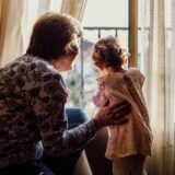 O bunică și nepoțica ei care frământă aluat împreună într-o bucătărie luminoasă, cu făină pe masă